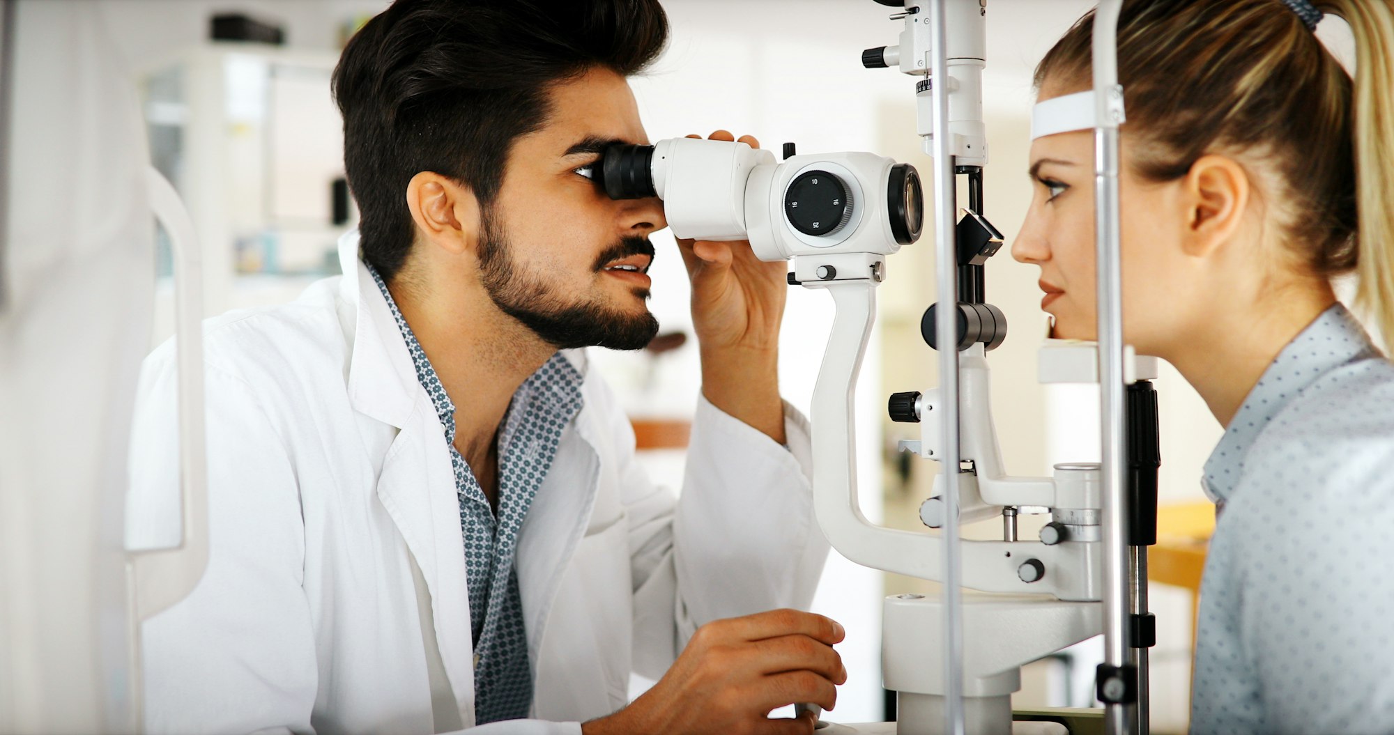 Attentive optometrist examining female patient on slit lamp